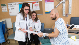two female pharmacists talking to a male patient in a hospital setting